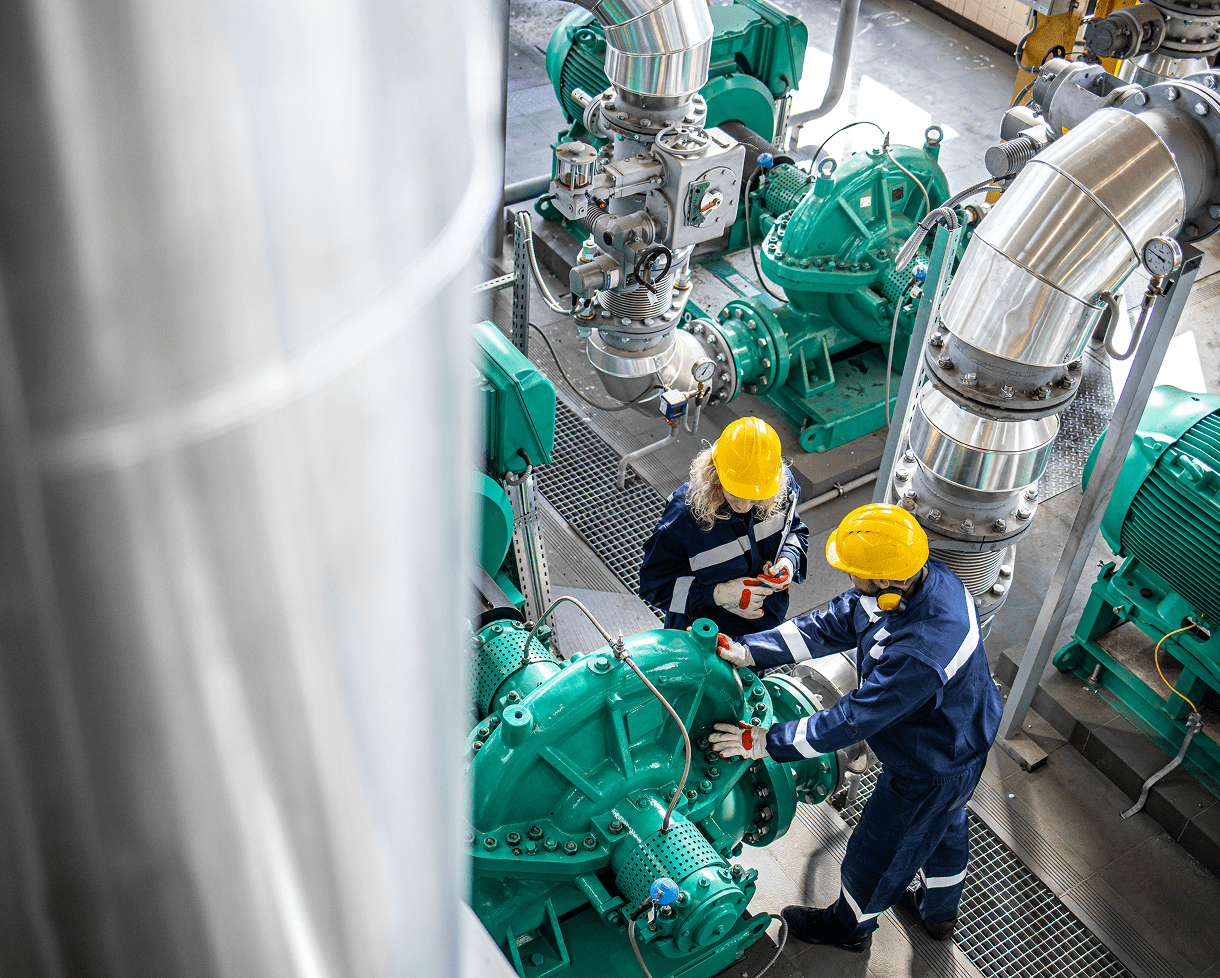 Workers inspecting industrial machinery with helmets.